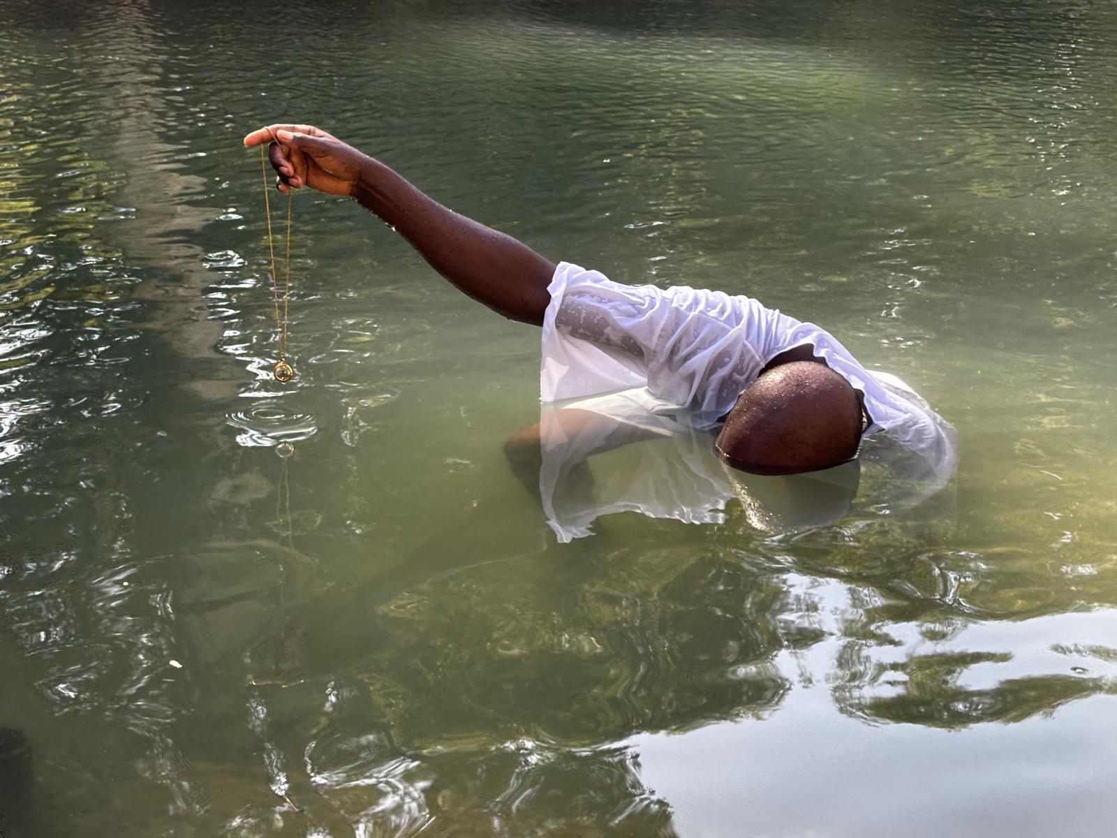 Person partially submerged in water, holding a string or rope.