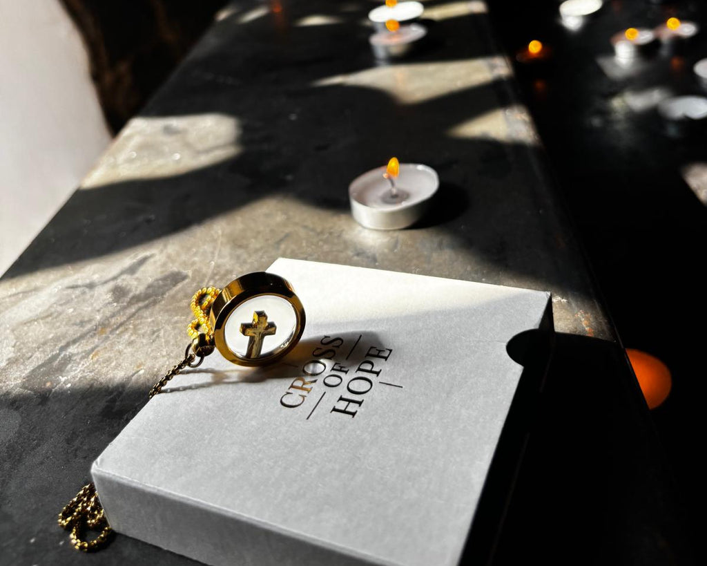 Book titled 'Credo of Hope' with a cross pendant on a dark surface with candles in the background.